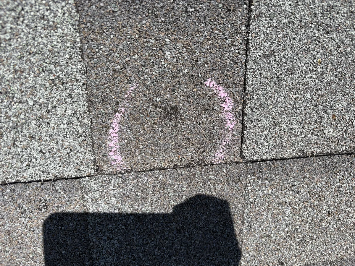 Chalk-circled hail strike on an asphalt shingle from claim documentation