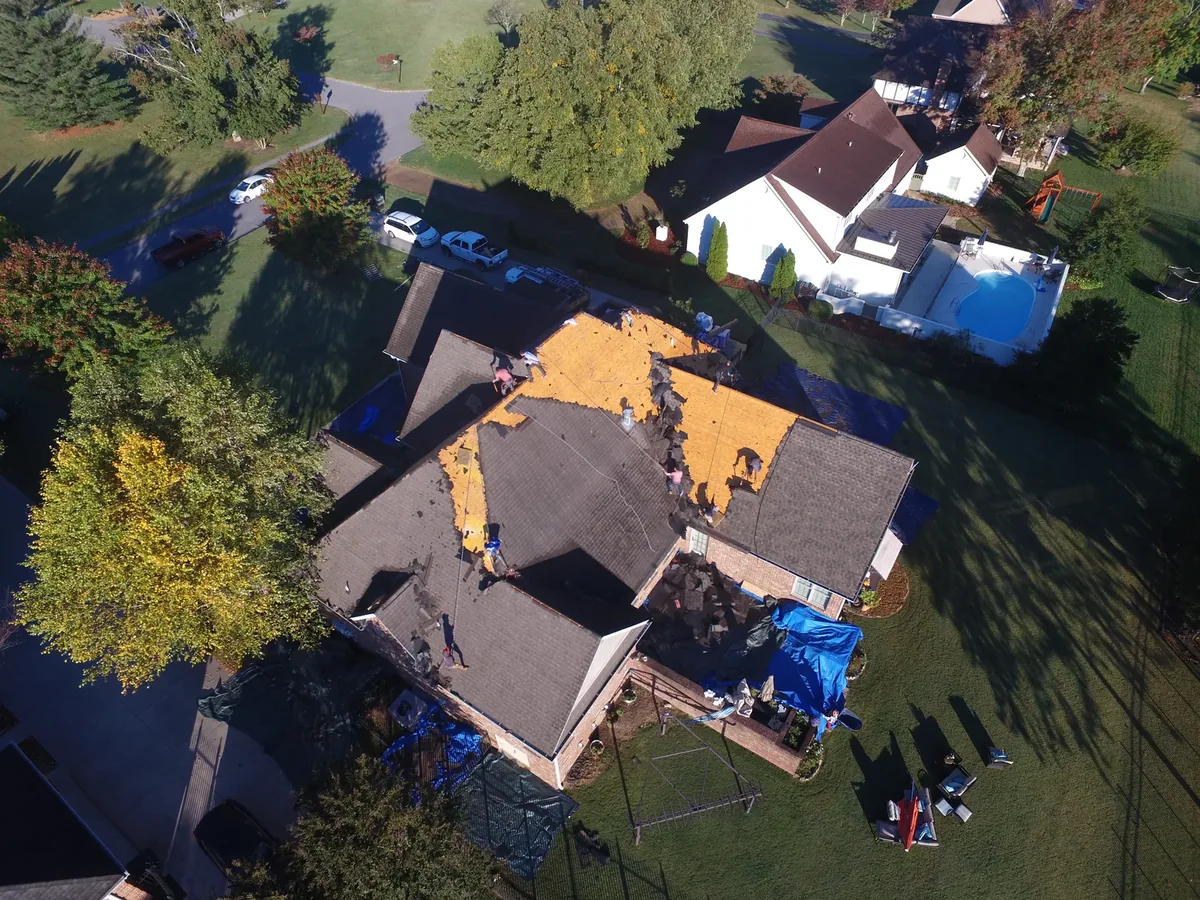 Roof tear-off in progress on a Tullahoma, TN home with tarps protecting landscaping