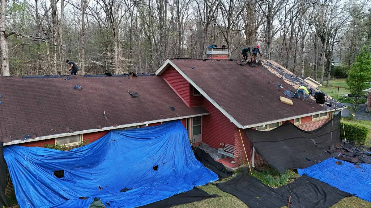 Roof replacement in progress on a red-sided home in Tullahoma, TN, tarps down